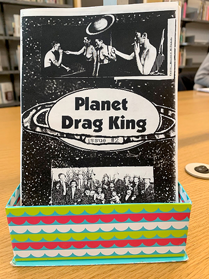photo of the zine Planet Drag King #2 in a colorful little basket that kind of resembles a stage