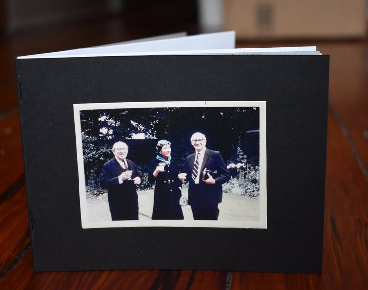 photo of an open zine with a color photo of three adults in dressy clothes holding champagne glasses