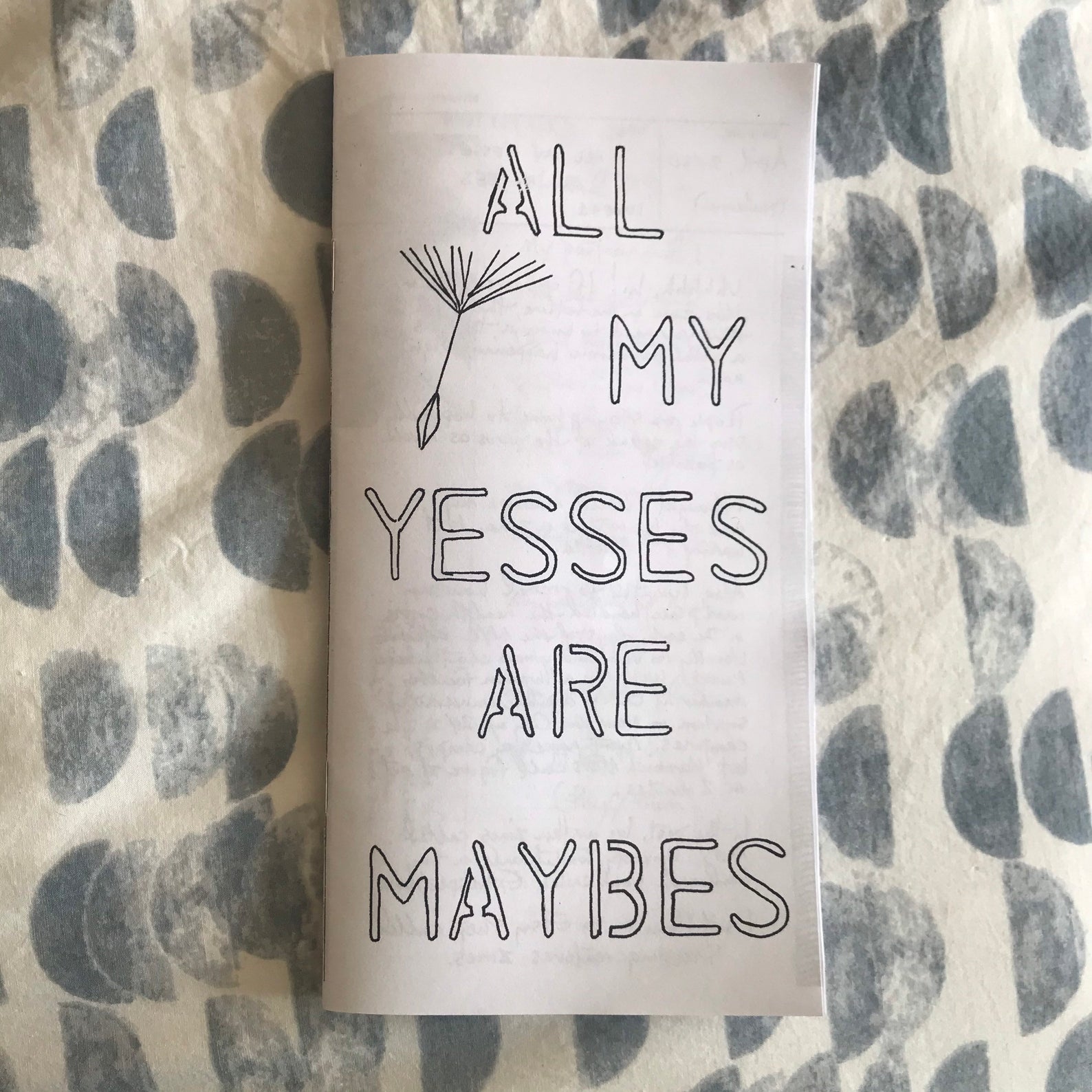 Zine: Ally My Yesses Are Maybe [black text on white background], on a half moon drape